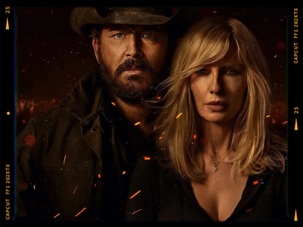 A dramatic portrait of a man wearing a cowboy hat and a rugged coat, standing closely to a woman with long blonde hair, both displaying serious expressions against a dark, fiery background.