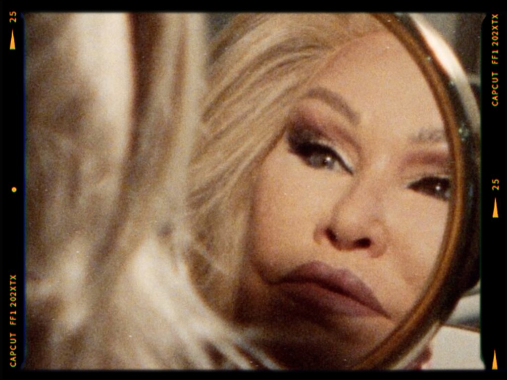 Close-up of a person looking into a mirror, highlighting their makeup and styled hair.